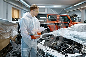 Young man mechanic looking at car engine