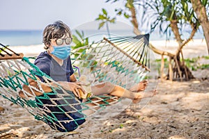 Young man in medical mask on the beach in a hammock with a drink Tourists fear the 2019-ncov virus. Medical masked