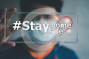 Young man in medical mask holding sign with stay home stay safe text. Social media campaign for coronavirus prevention