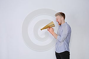 Young man with megaphone on light background