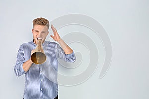 Young man with megaphone on light background