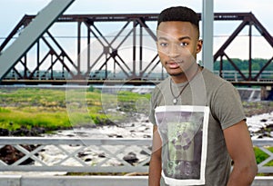 Young man on metal bridge structure, river and railway beams