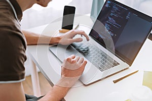 Young man mobile developer, programmer writes program code on a laptop