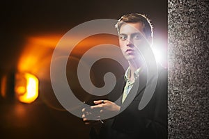 Young man with a mobile phone standing at the wall