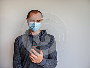 Young man with mobilphone wearing a protective medicine mask isolated on white background