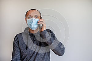 Young man with mobilphone wearing a protective medicine mask isolated on white background photo