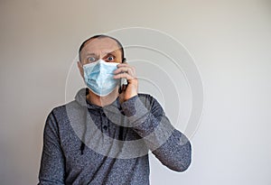 Young man with mobilphone wearing a protective medicine mask isolated on white background. COVID-19 pandemic concept. Copy space photo