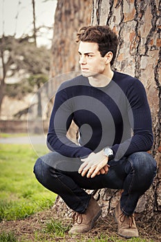 Young man model in a park under a tree photo