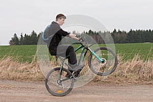 Young man on mountain bike jumping on path.