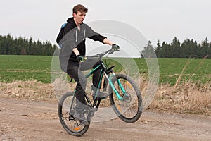 Young man on mountain bike jumps on path