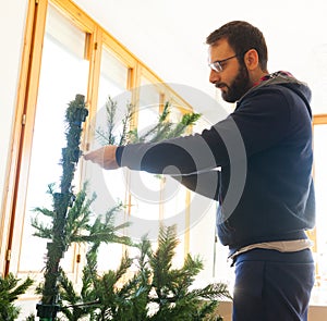 Young man mounting artificial Christmas tree