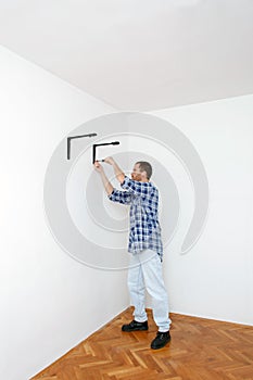 Young man mounting shelf carriers onto the wall