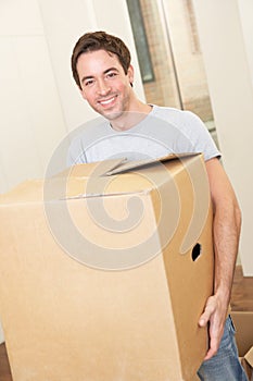 Young man on moving day carrying cardboard box