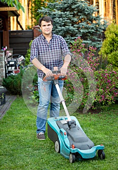 Young man mowing grass at house backyard