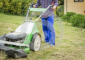 Young man mowing the lawn with a lawnmower