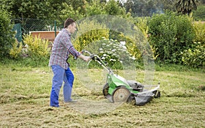 Young man mowing the lawn with a lawnmower