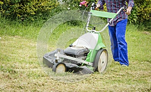 Young man mowing the lawn with a lawnmower