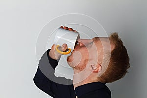 A young man with a mug of tea or coffee. He pleased. White background. Redhead male with white mug.