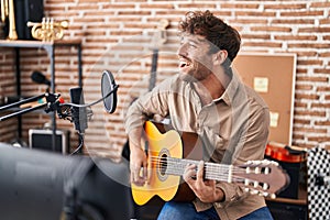 Young man musician singing song playing classical guitar at music studio