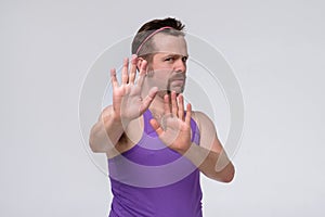 Young man with mustache coving away hands palms showing refusal and denial gesture