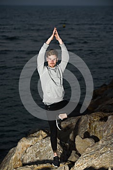 Young man in a Namaste greeting position while freeing his mind from worries in tree pose