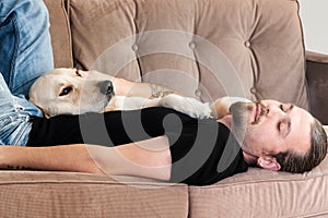 Young Man Napping on Sofa with Dog