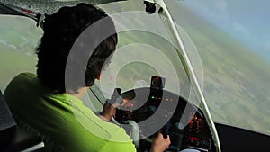 Young man navigating flight simulator, maneuvering steering wheel, video game
