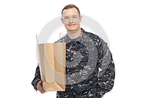 Young man in navy uniform with grocery store paper bag