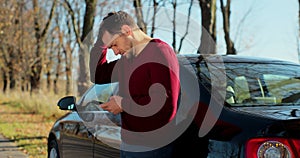 A young man near a broken car uses a mobile phone to call an emergency service. Concept road accident. Help repair.