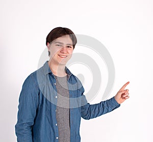 Young man nerd pointing finger aside at blank copy space, isolated on white grey studio background