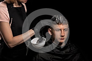 Young man with new haircut. Professional hairstyle. Model and trendy hairdressed. Barber is coloring male hair. Handsome guy in