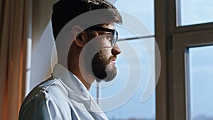 Young man nurse with a eyes glasses take a break in the hospital he looking through the panoramic window