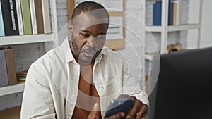 Young man in office using smartphone focused on work in a modern indoor workplace setting