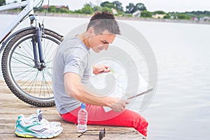 Young man, one happy tourist bicyclist with route map wearing in gray shirt