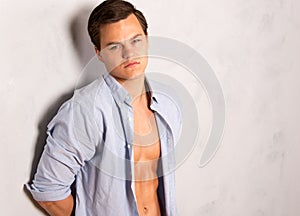 Young man in open shirt leaning against wall