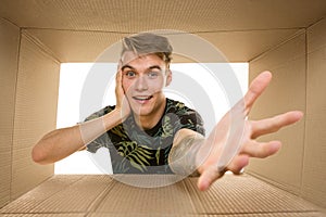 Young man opening the biggest postal package isolated on white