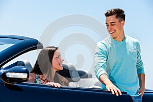 Young man opening car door to woman.