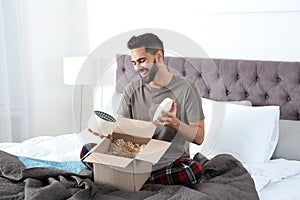 Young man opening parcel in bedroom