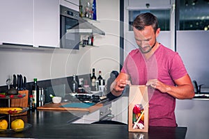 Young man opens a package of fresh ingredients to make a healthy dinner