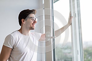 Young man opens the window. Ventilating a house in hot weather