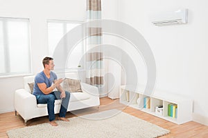 Young Man Operating Air Conditioner