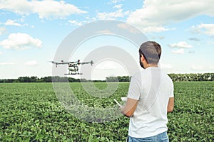 Young man operating of flying drone octocopter at the green field.