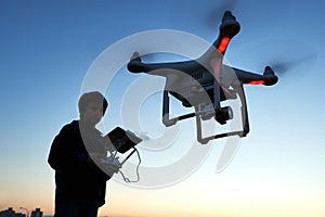 Young man operating of flying drone at sunset