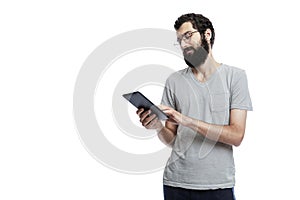 A young man in oracle and with a beard with a flat in his hands looks at the screen. Blogging, online communication and social