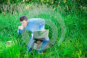 Young man outdoors with a cup and laptop