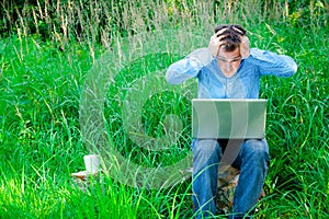 Young man outdoors with a cup and laptop