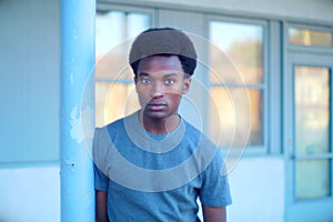 Young man outside orange sunlight windows urban concrete pole city