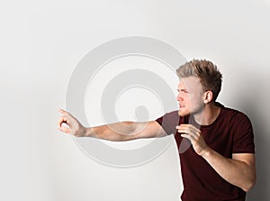 Young man outstretching hand on light background