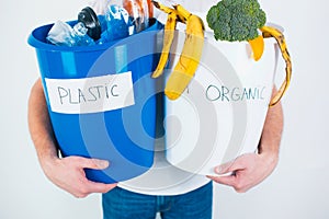 Young man  over white background. Cut view of a guy holding separated buckets with organic and plastic waste