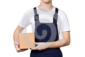 Young man in overalls holding cardboard box in hands, isolated on white